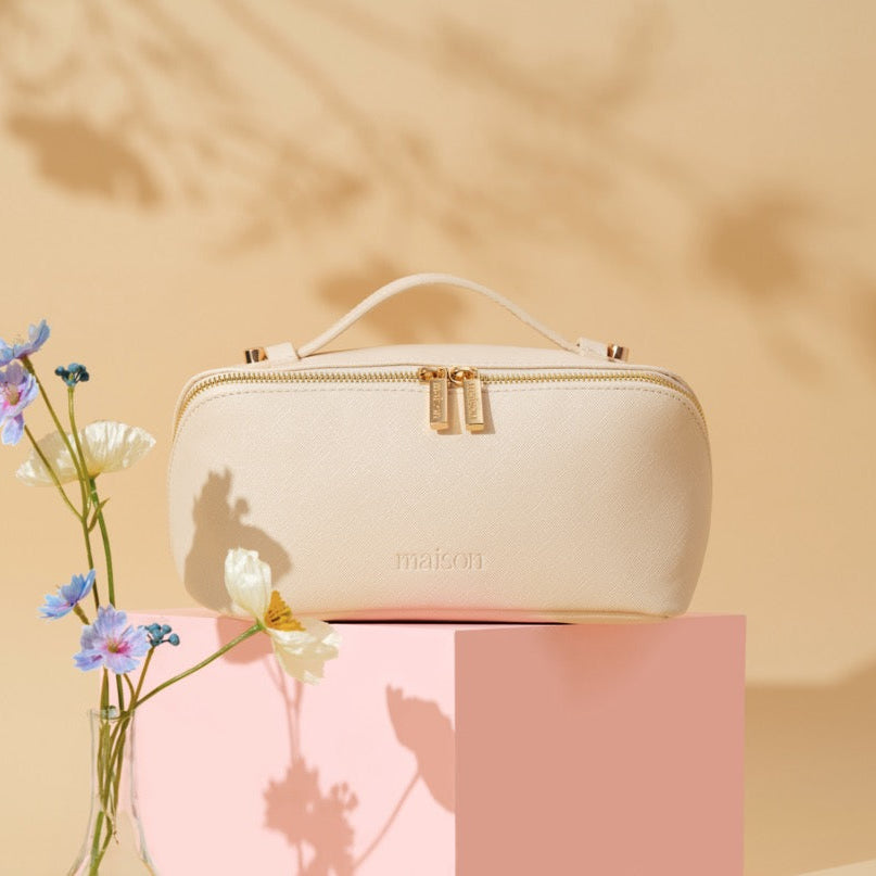 Cream-colored cosmetic bag with floral arrangement on a beige background