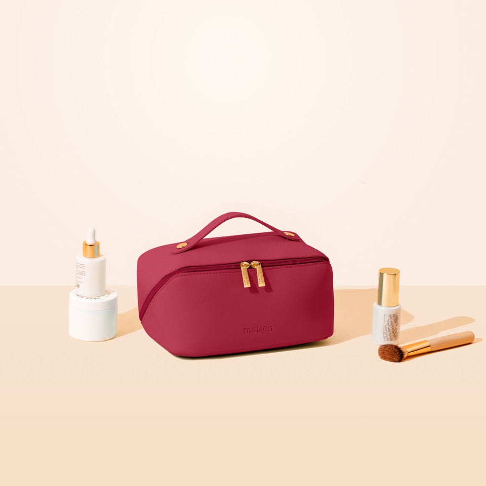 Red cosmetic bag with skincare products on a beige background